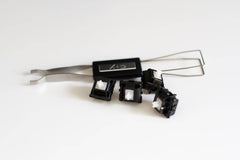 A few Durock POM linear mechanical keyboard switches next to a CY stainless steel switch puller.