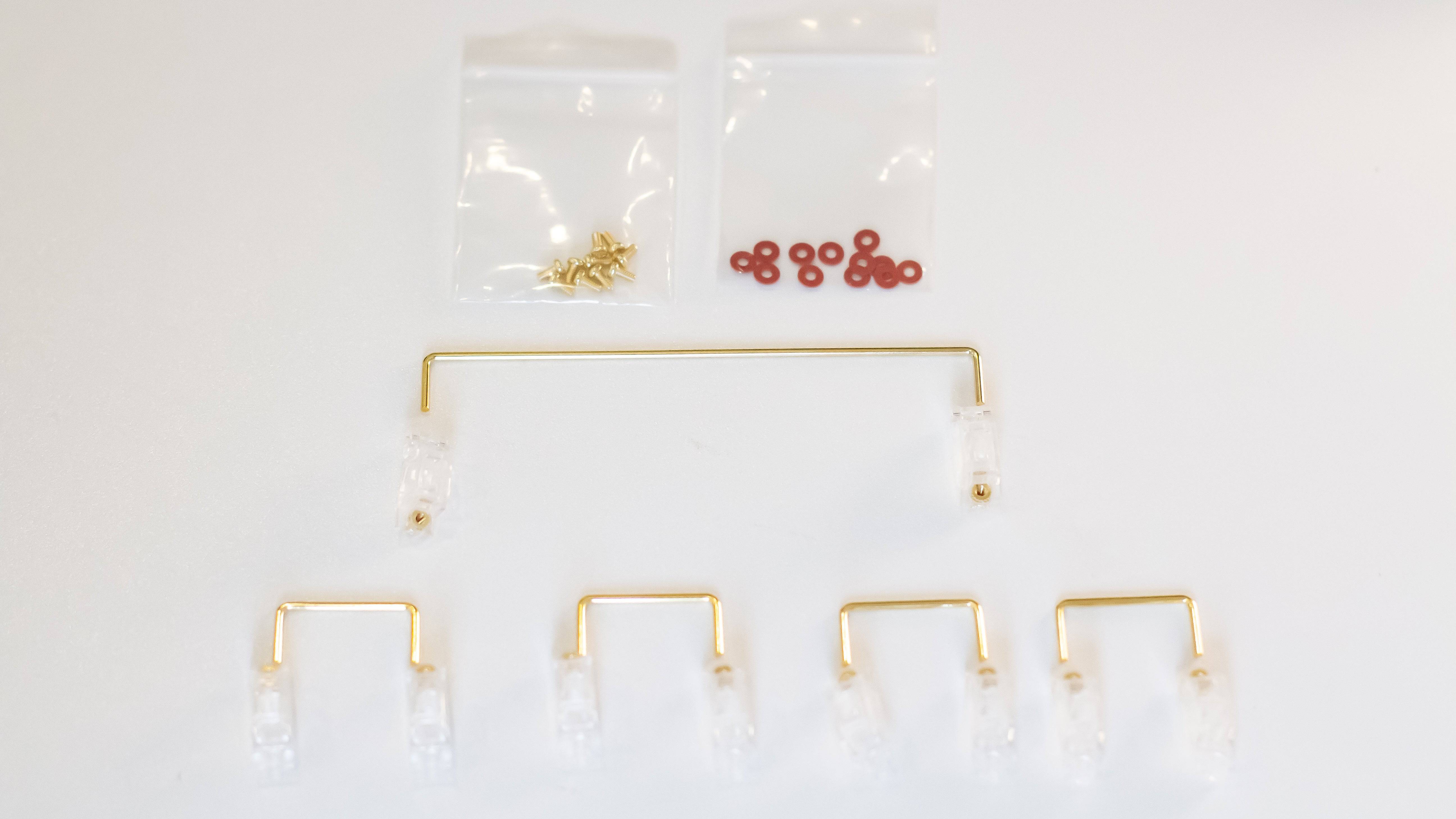 Clear Durock V2 stabilizers with gold wires, gold screws, and red screw dampener pads for DIY mechanical keyboards..