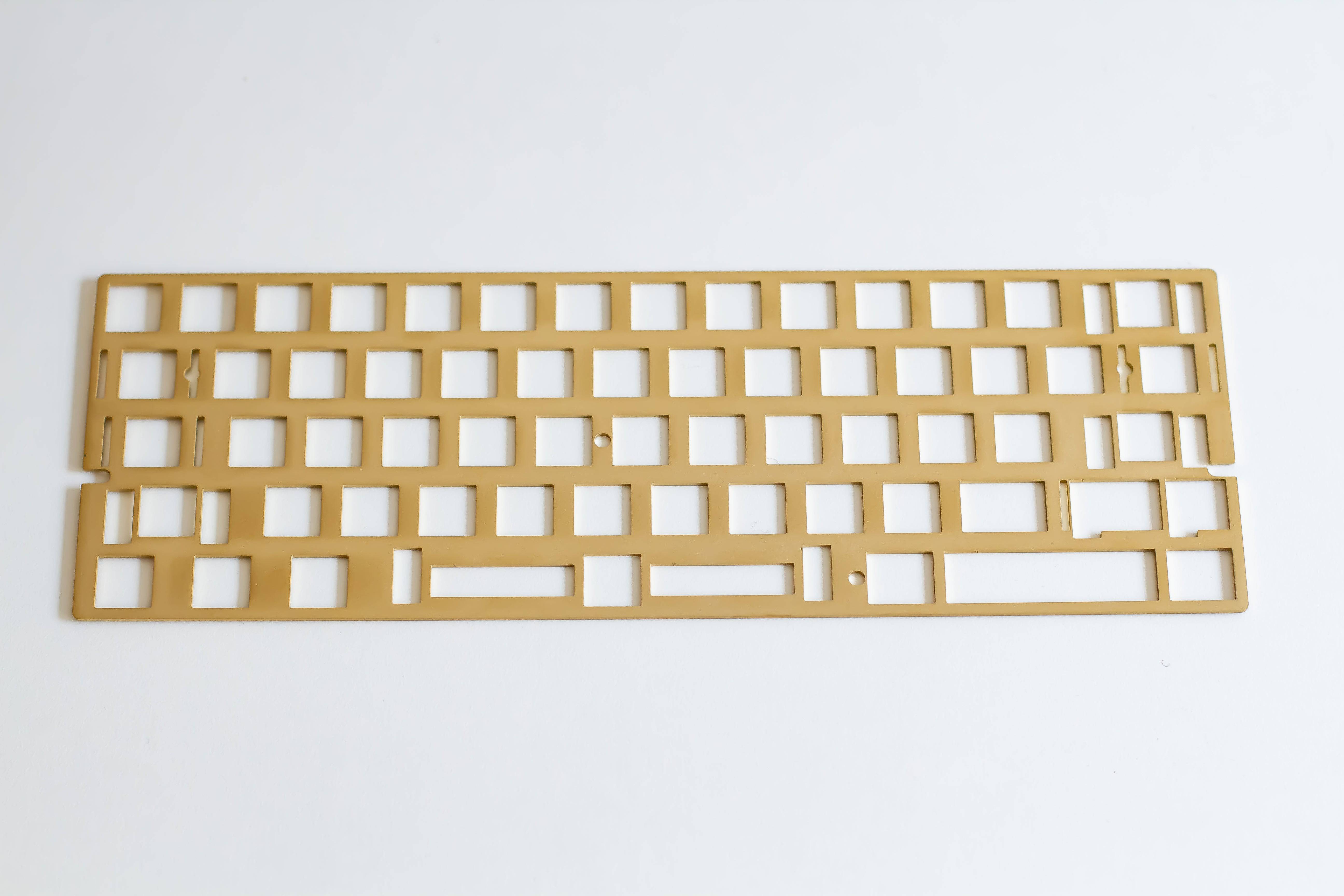 Angled top down view of the FB60/Freebird60 universal ANSI brass mechanical keyboard plate.