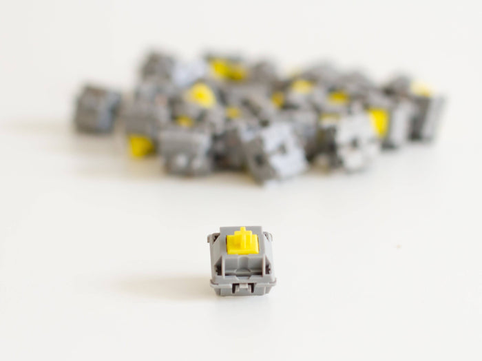 A batch of JWK Durock tactile POM T1 sunflower mechanical keyboard switches with one switch at the front.