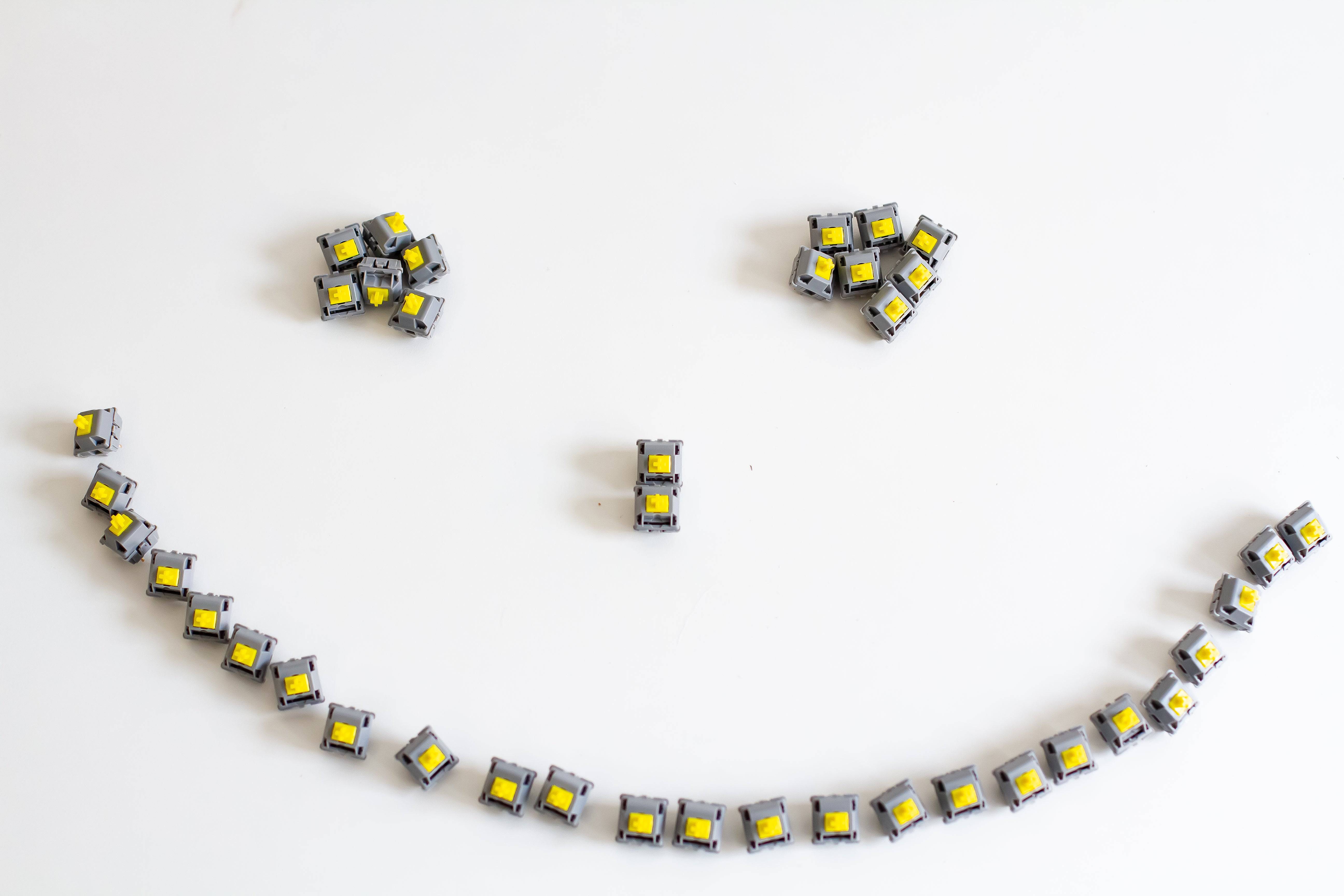 A batch of JWK Durock POM Tactile T1 sunflower mechanical switches arranged in a smiling face.